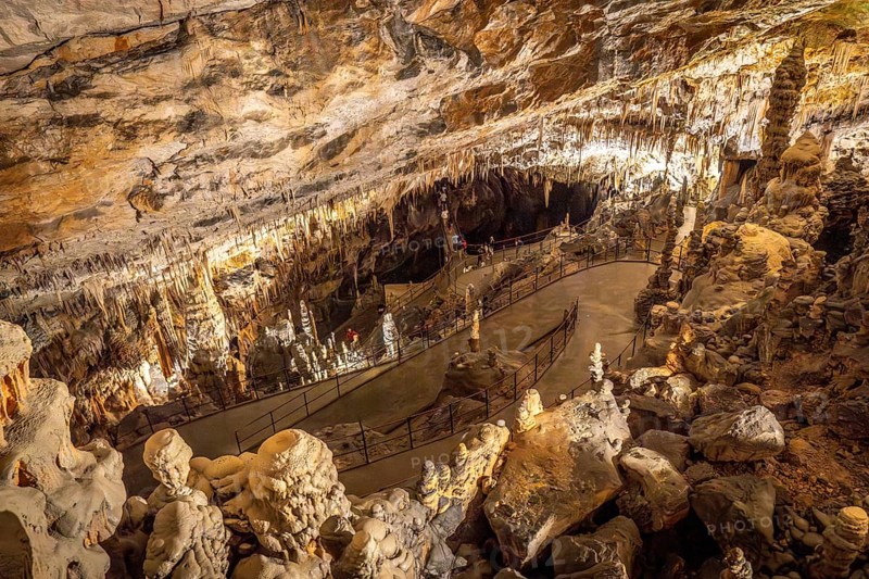 Tourists walking on illuminated footpath inside the famous postojna cave, a karst cave system near postojna, slovenia