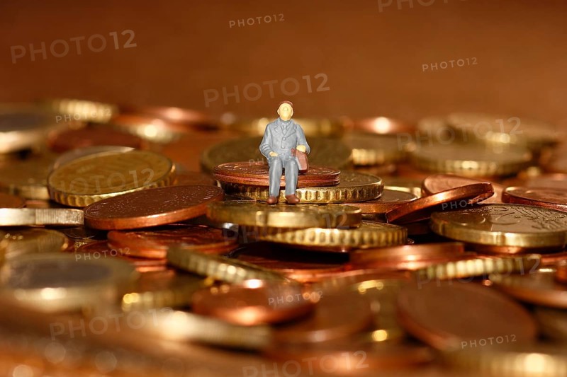 Miniature man sitting among euro coins, North Rhine-Westphalia, Germany, Europe