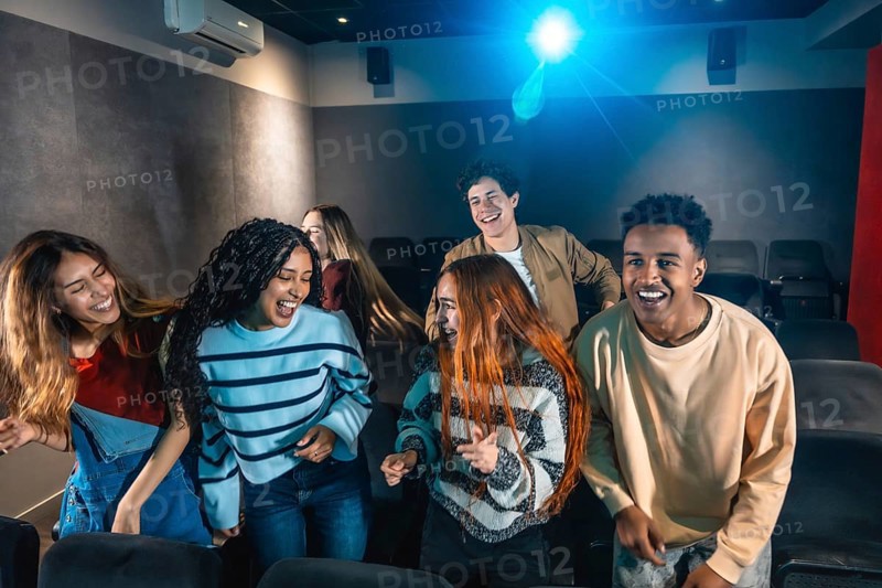 Happy multi ethnic friends dancing and celebrating together at a lively movie disco event in the cinema, enjoying every moment of fun