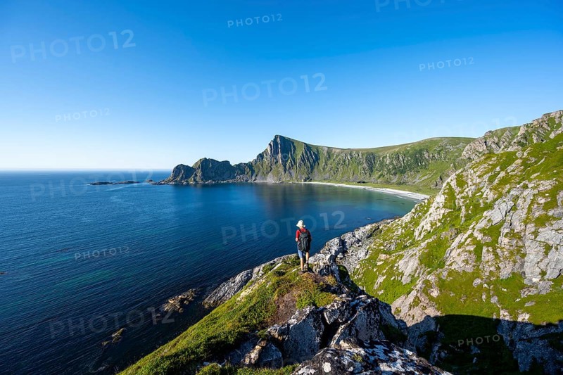 Mountaineer with view of coastal landscape, steep coast with peak Måtind, Høyvika beach and sea, hike to the peak of Måtind, Andøya island, Vesterålen, Nordland Norway