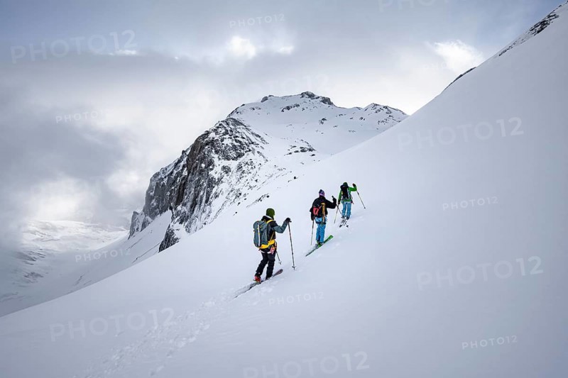 Three ski tourers in a snowy mountain landscape in the morning light, ascent to the Wildhorn, cloudy mood, high tour, Bernese Alps, Bernese Oberland, Switzerland, Europe