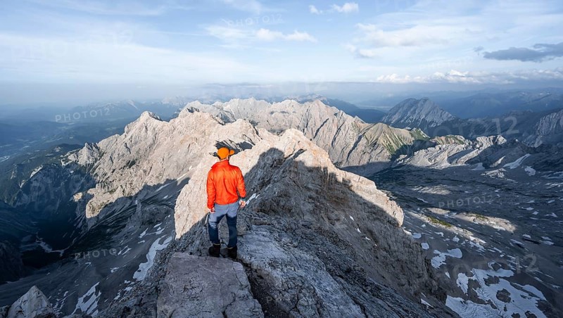 Mountaineer on a narrow rocky steep ridge, view of the Höllental and the Alpspitze from the Jubiläumsgrat, in the evening light Zugspitze, Wetterstein range, Bavaria, Germany, Europe