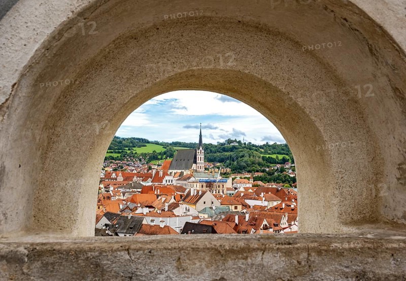 View of Ceský Krumlov town through a stone arch, featuring rooftops and church steeple, Cesky Krumlov, Czech Republic, Europe