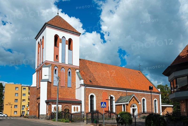 Historic church with brick tower in front of cloudy sky in city neighbourhood, Dominikuskirche, Ostroda, Osterode in East Prussia, Warminsko-Mazurskie, Poland, Europe