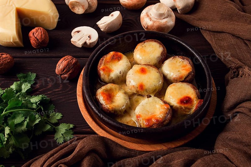 Traditional Georgian dish, appetizer, stuffed mushrooms, Sulguni cheese, baked in a Ketzi clay pan, on a wooden table, close-up, no people