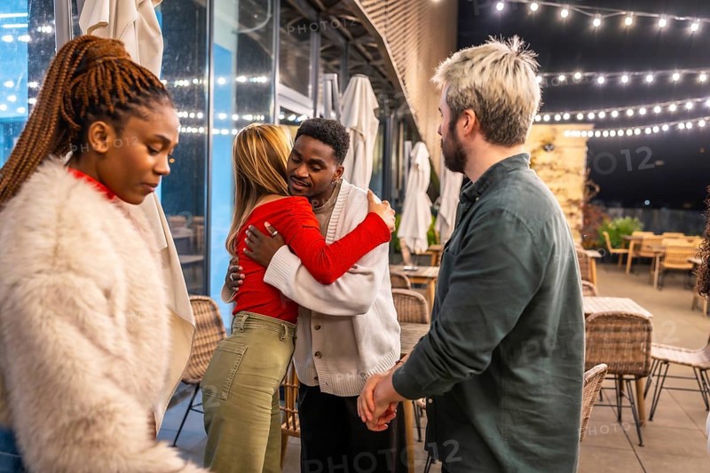 Multiracial friends saying goodbye after a dinner on a terrace at night