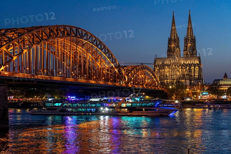 Cologne Cathedral, has been shining in new light since Easter 2025, the old metal halide lamps have been replaced by over 700 modern LED lamps, reducing energy consumption by around four-fifths, significantly improving the quality of light and greatly reducing light emissions, 12 KM of new cables were laid for this, KD Party Schiff, Hohenzollernbrücke, railway bridge over the Rhine, North Rhine-Westphalia, Germany, Europe