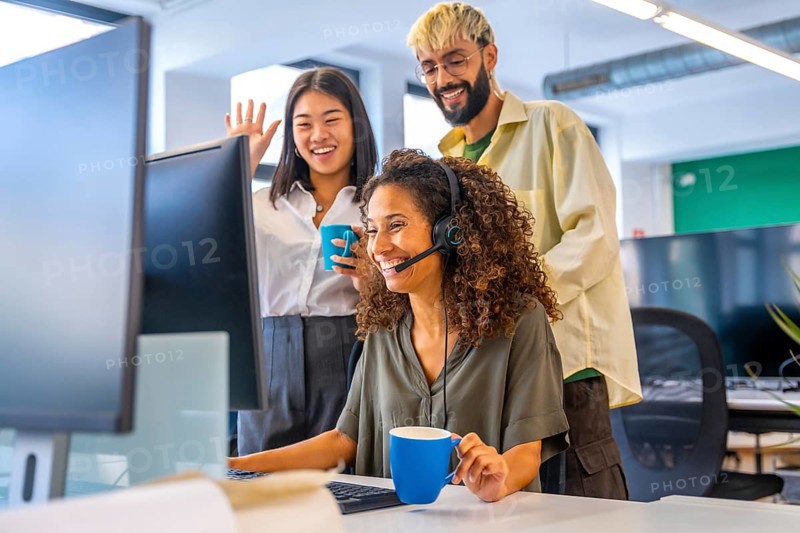 Coworkers drinking coffee and waving while making a video call suing headset