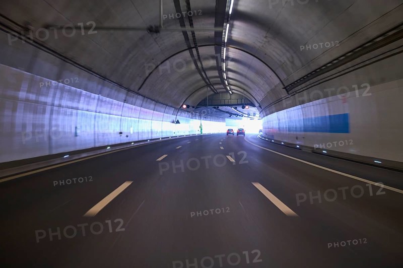 Modern, well-lit motorway tunnel with blue illuminated walls and a clear asphalt road, Switzerland, Europe