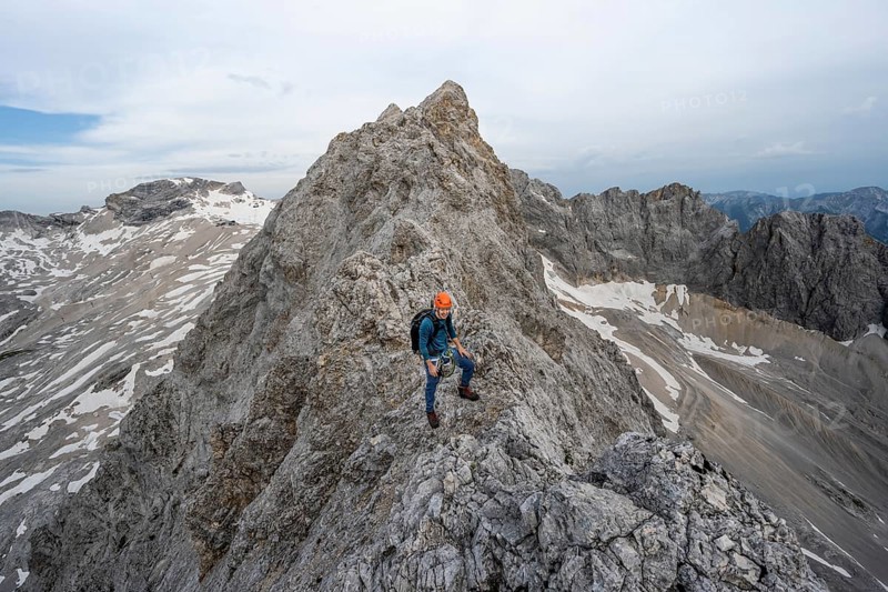 Mountaineer with helmet on a narrow rocky ridge, crossing the Jubiläumsgrat, Wetterstein range, Bavaria, Germany, Europe