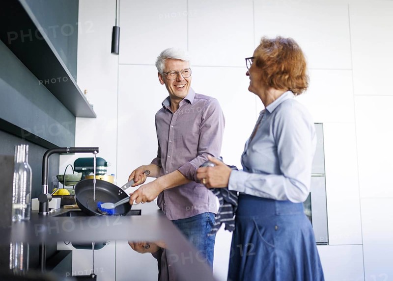 Symbolic photo. An elderly couple stand in the kitchen and do the washing up together. Berlin, 13.08.2024
