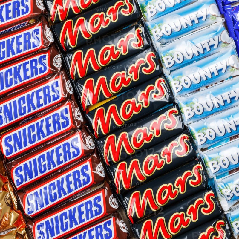 Mars Incorporated products such as Snickers chocolate bars, Twix, Milky Way and Bounty bars as a square background