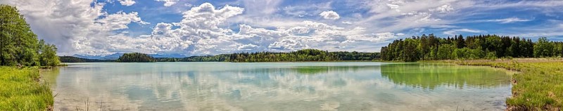 Lake with clear water surface, cloudy sky and surrounding green nature, Easter Lakes