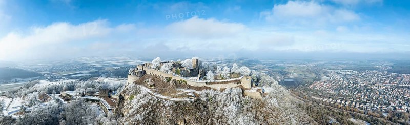 Aerial panorama of the snow-covered Hegau volcano Hohentwiel with Germany's largest castle ruins, surrounded by frosty trees in a winter landscape, on the right the town of Singen, district of Constance, Baden-Württemberg, Germany, Europe