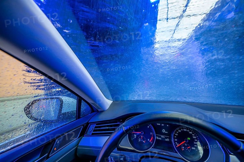 Car in an automatic car wash, car wash tunnel, cleaning foam is sprayed on, rotating brushes clean the vehicle