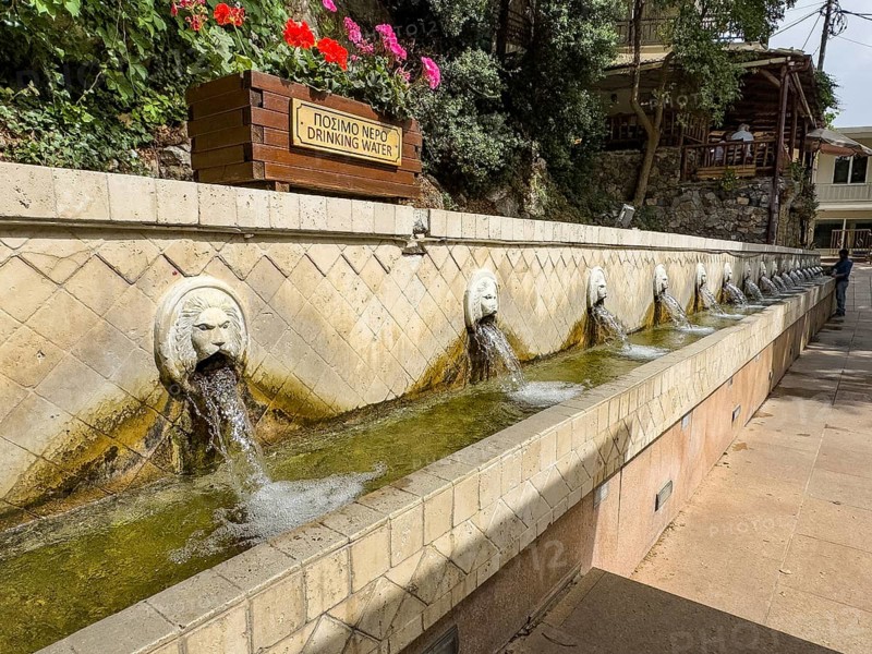 Partial view of lion fountain Venetian fountain Kefalovrisi with 25 waterspouts in the shape of lion's head Lion's head above Plla chain sign Drinking water Drinking water below Catch basin with drinking water on main square of village Spili, Spili, Crete, Greece, Europe