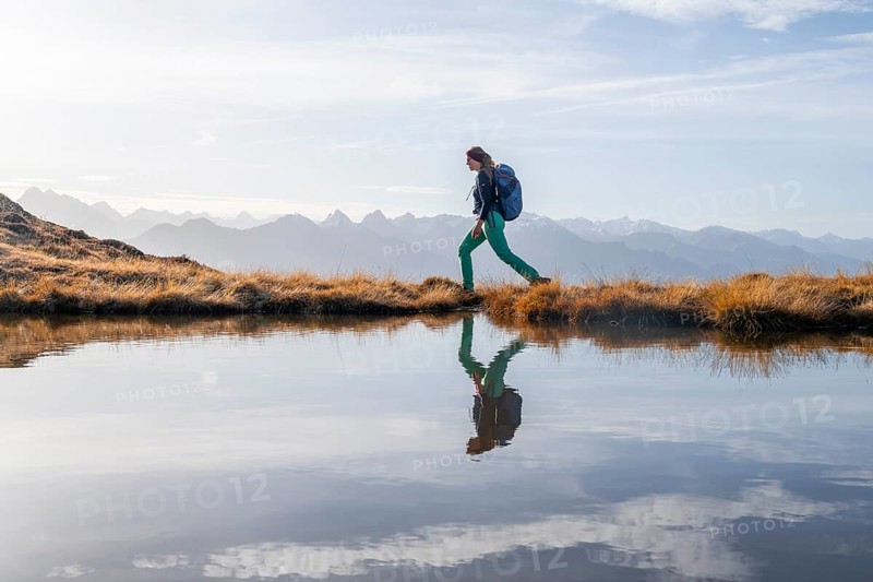 Hiker reflected in a small mountain lake on the Krahberg, mountain panorama in autumn, Venet crossing, Ötztal Alps, Tyrol, Austria, Europe