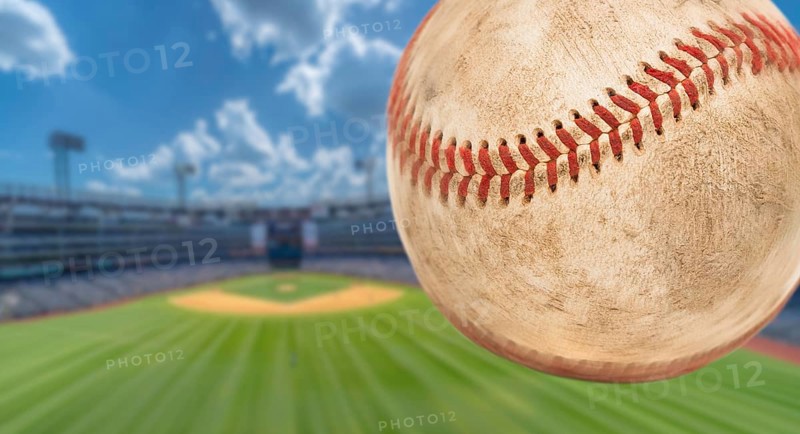 Baseball flying through the air with stadium in the background