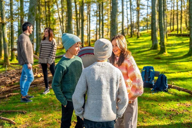 Caucasian family with three teens having fun during a camping in a green alpine forest