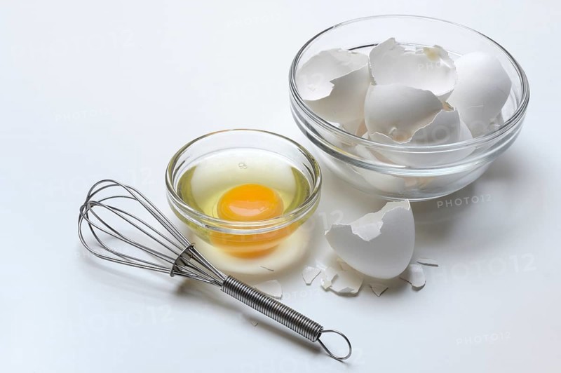 Egg whites and egg yolks in glass bowl and egg shells, whisk