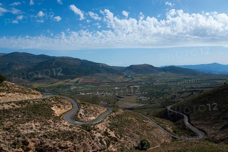 Mountain landscape with serpentine road in green valley under blue sky with clouds, road to Mirador Laujar, Laujar de Andarax, Almería province, Almeria, Andalusia, Spain, Europe