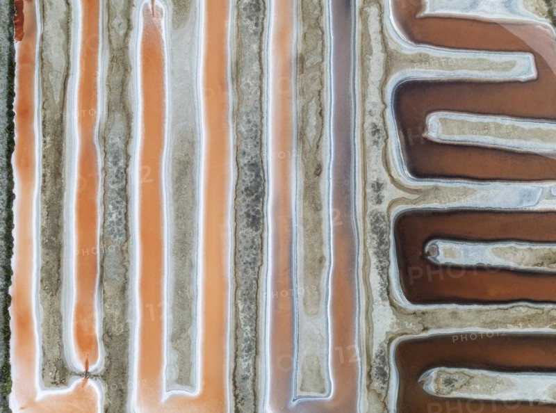 Saline ponds at the salt works near Chiclana de la Frontera. The orange-red colour depends on the level of salinity and is directly caused by the algae Dunaliella salina and brine shrimp. Aerial view. Drone shot. Cádiz province, Andalusia, Spain, Europe