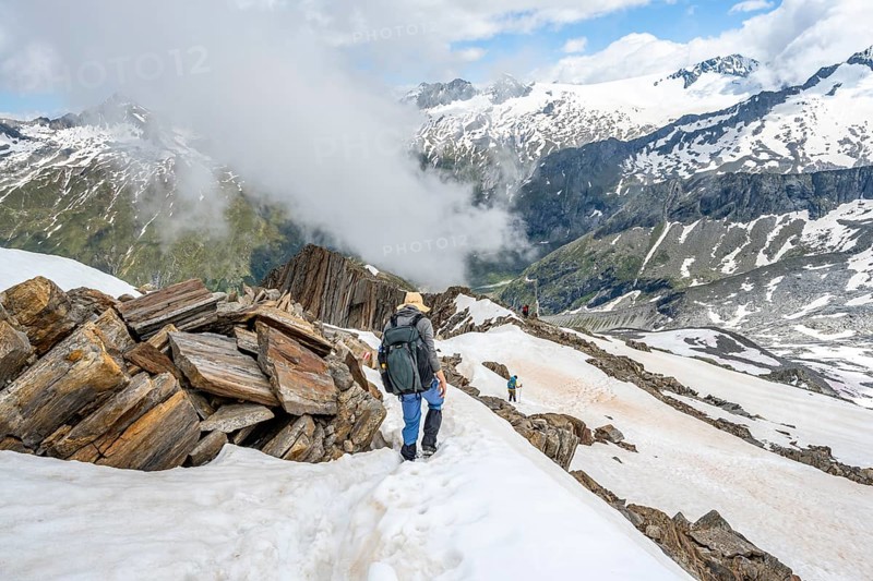 Mountaineer on a rocky ridge with snow, descent from the summit of Schönbichler Horn, view of snow-covered mountain peaks and valley Zemmgrund, Berliner Höhenweg, Zillertal Alps, Tyrol, Austria, Europe