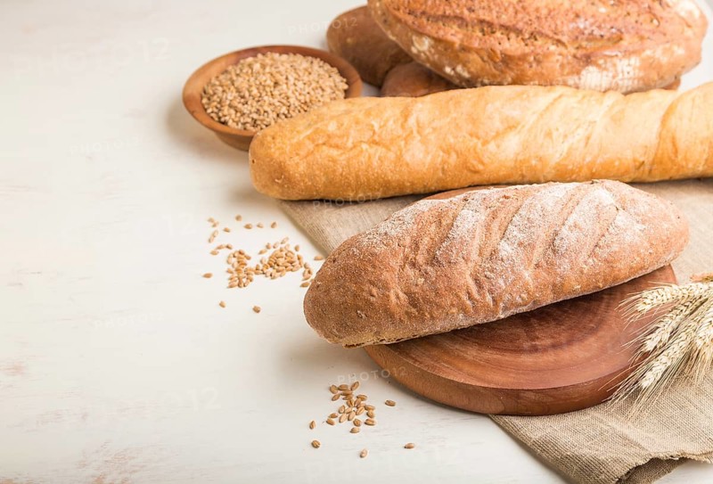 Different kinds of fresh baked bread on a white wooden background. side view, close up, copy space