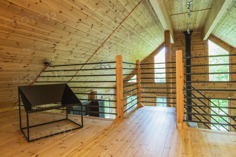Black metal sitting chair and tubular railings with wooden posts in home office set-up on mezzanine inside a piece sur piece Scots pine log home, Quebec, Canada, North America