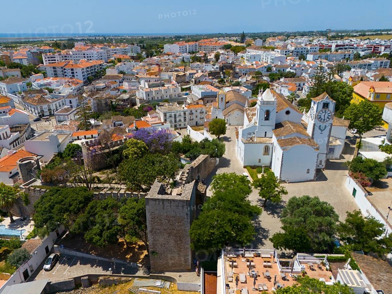Aerial view of a town with churches, a striking clock tower and old walls, surrounded by a roofscape and many trees, Tavira, Faro, Algarve, Portugal, Europe