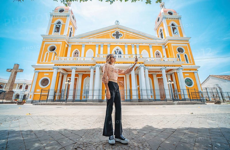 Beautiful tourist taking a selfie on the street of the cathedral in Granada, Nicaragua Young woman traveler taking a selfie in a public square in front of a cathedral