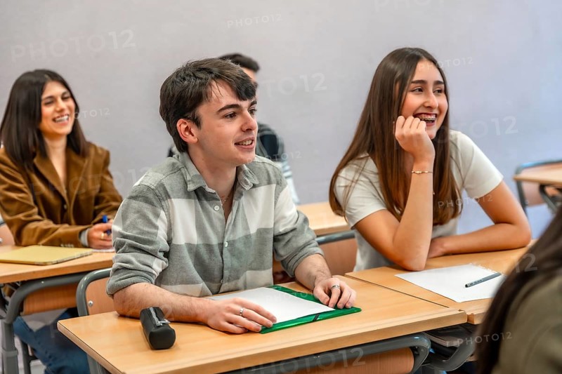 Group of happy and smiling students listening to their teacher in a classroom at their university or institute