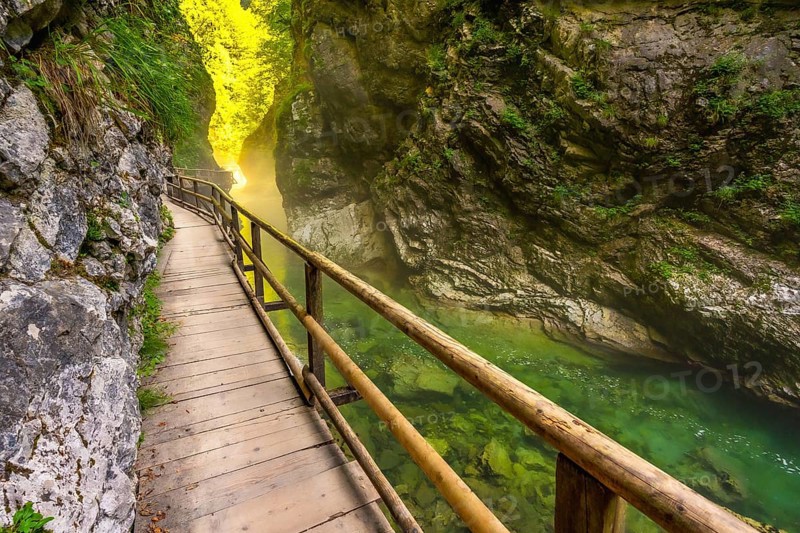 Scenic wooden walkway winds through vintgar gorge, showcasing stunning emerald waters and lush canyon walls in slovenia