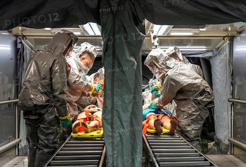 Decontamination of injured persons after an assumed accident involving hazardous substances, fire brigade and aid organisations practise setting up and operating a decontamination station, injured persons are sighted and then washed in a special shower tent to remove possible hazardous substances and chemicals in order to avoid further injuries, the emergency services wear special, ventilated protective suits, large-scale exercise by the Essen fire brigade