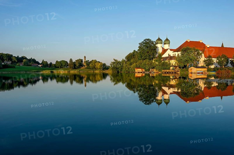 Romanesque Benedictine abbey Seeon monastery, monastery church St. Lambert with reflection in the monastery lake, calm smooth water in the evening light at sunset, behind the side church Maria zu Breuhausen, also Bräuhausen, Seeon-Seebruck, Chiemgau, Upper Bavaria, Bavaria, Germany, Europe
