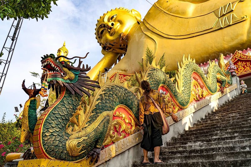 Tourist in front of the huge reclining Buddha statue of the Buddhist temple Wat Mokkanlan in Chom Thong, Thailand, Asia
