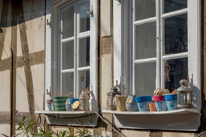 Two mullioned windows in a half-timbered house, window sills decorated with flower pots and lanterns, Alsace, France, Europe
