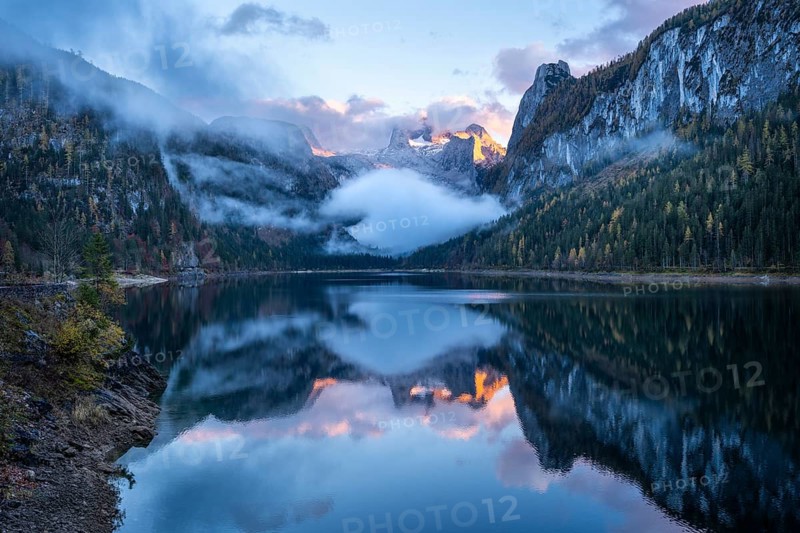 The Vordere Gosausee lake in autumn with a view of the Dachstein mountain range. The Gosaukamm on the right. Blue sky and clouds. In the evening at sunset. Reflection. Vorderer Gosausee, Gosau, Gosau valley, Salzkammergut, Upper Austria, Austria, Europe