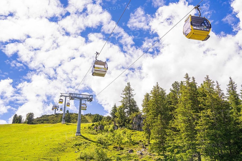 Several cable cars travelling across a green meadow under a cloudy sky, Penken, Zillertal, Austria, Europe