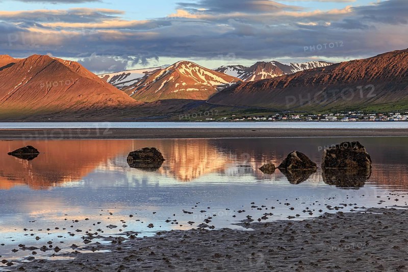 Fjord, low tide, stones, mountains reflected in the water, evening light, cloudy mood, Thingeyri, Westfjords, Iceland, Europe