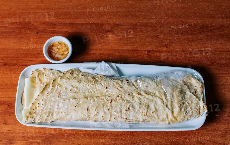 Delicious traditional Nicaraguan quesillo served on wooden table, View of a Nicaraguan quesillo served on table. Top view of Nicaraguan Quesillo on a plate served on wooden table