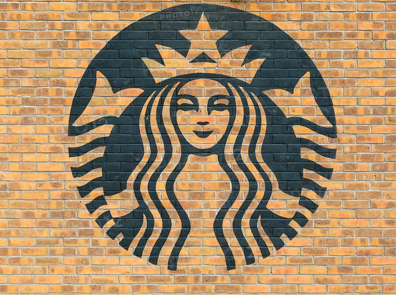 Starbucks coffee logo symbol stencilled onto wall of yellow bricks, Liverpool, Merseyside, England, UK