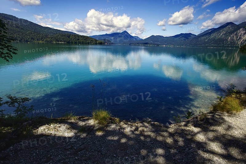 A calm lake reflecting the clouds and mountains, framed by wooded hills, Walchensee, Kochel am See, Bavaria, Germany, Europe