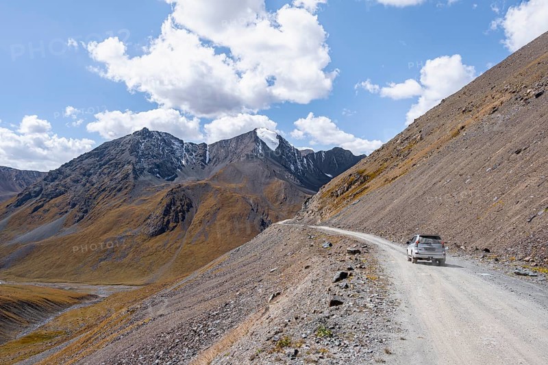 Car on narrow gravel track in mountain landscape at Chong Ashuu Pass, Tian Shan Mountains, Issyk-Kul, Kyrgyzstan, Asia