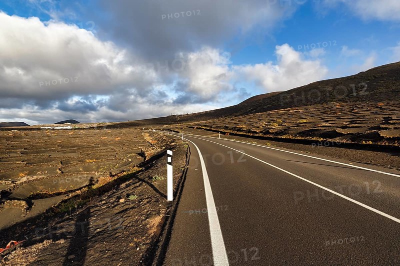 Empty country road through wine-growing area, typical landscape with volcanic mountains, La Geria, Lanzarote, Spain, Europe