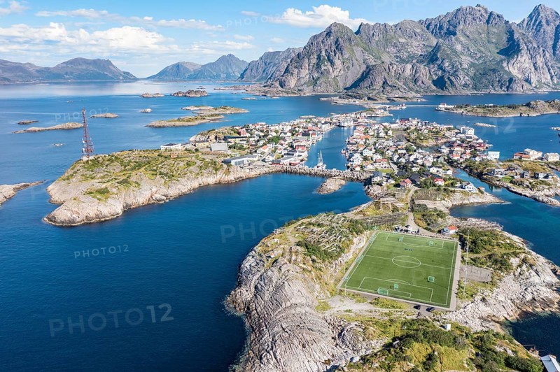 Aerial view over fishing village Henningsvaer, football stadium on rocky island, Lofoten, Norway, Europe