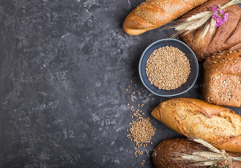 Different kinds of fresh baked bread on a black concrete background. top view, flat lay, copy space