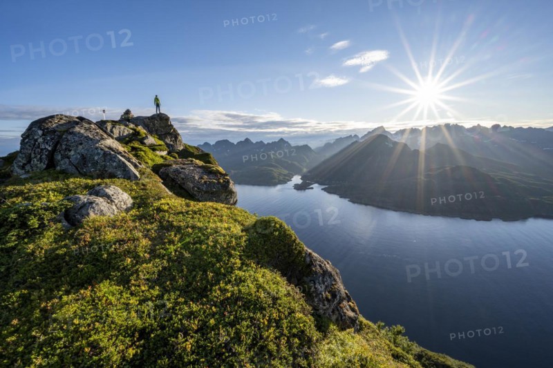 Mountaineer on the summit of Dronningsvarden or Stortinden, behind sea and fjord Umvågsundet, Sonnenstern, Vesterålen, Norway, Europe
