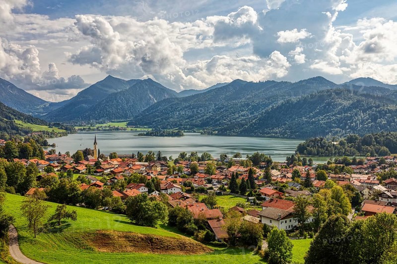 Picturesque lakeside village in the Alps, surrounded by green meadows and mountains under a cloudy sky, Schliersee