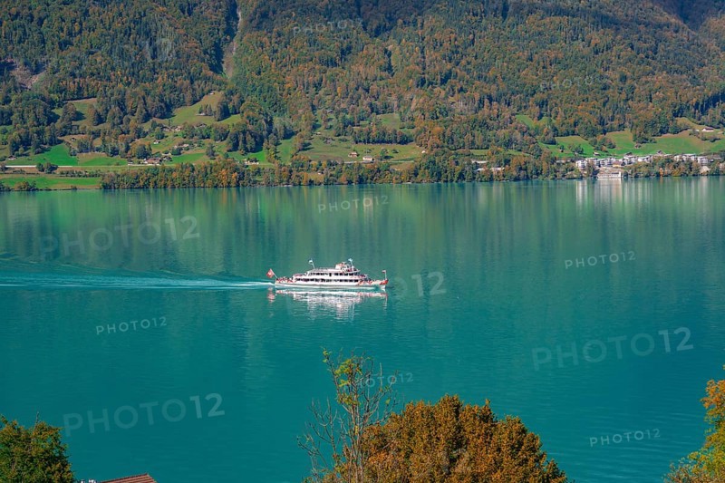 A boat sails across a calm lake in front of a picturesque mountain landscape, Lake Brienz, Switzerland, Europe